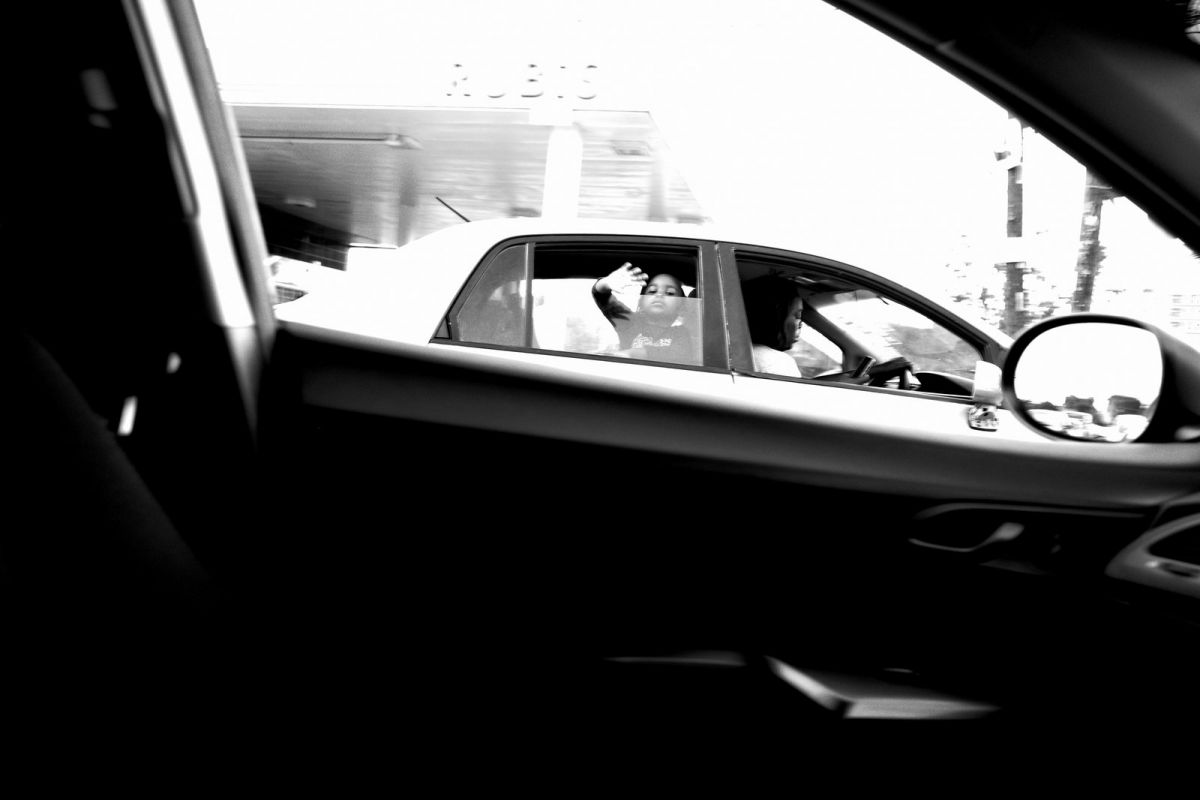 Boy/girl waving from car while at stop light